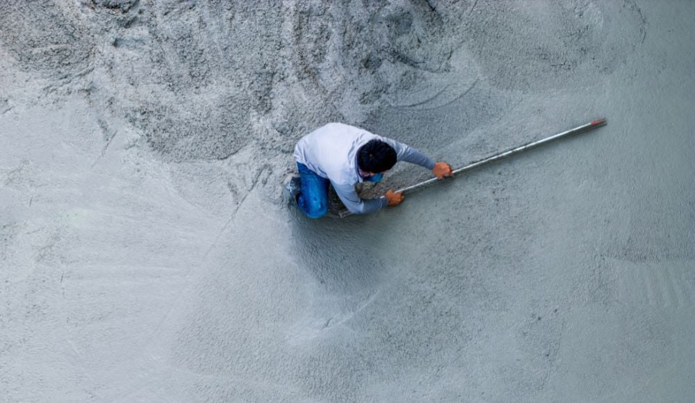 Ouvrier du bâtiment lissant le ciment humide avec une truelle. Chantier, travaux de béton, industrie du bâtiment. Vue de dessus Aérienne.